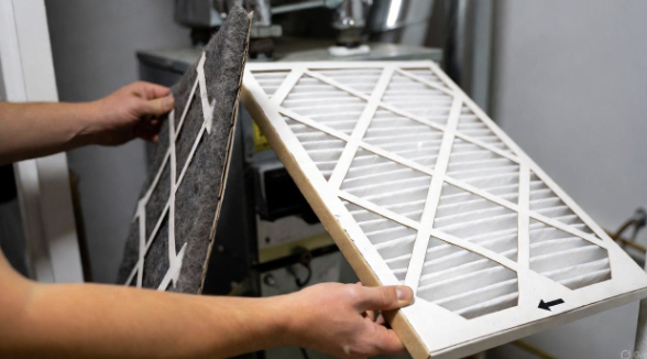 Hands sliding a clean HVAC filter into a return slot