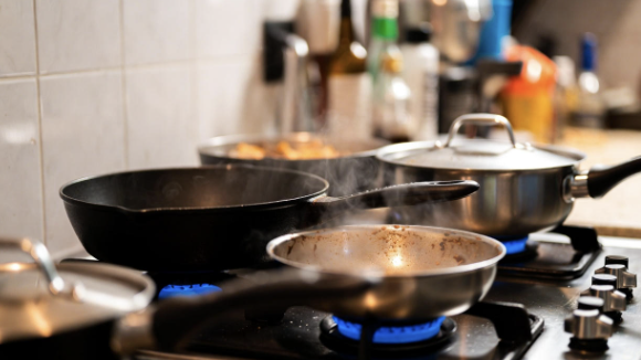 Cast iron and steel pans resting on a stove cooling after use