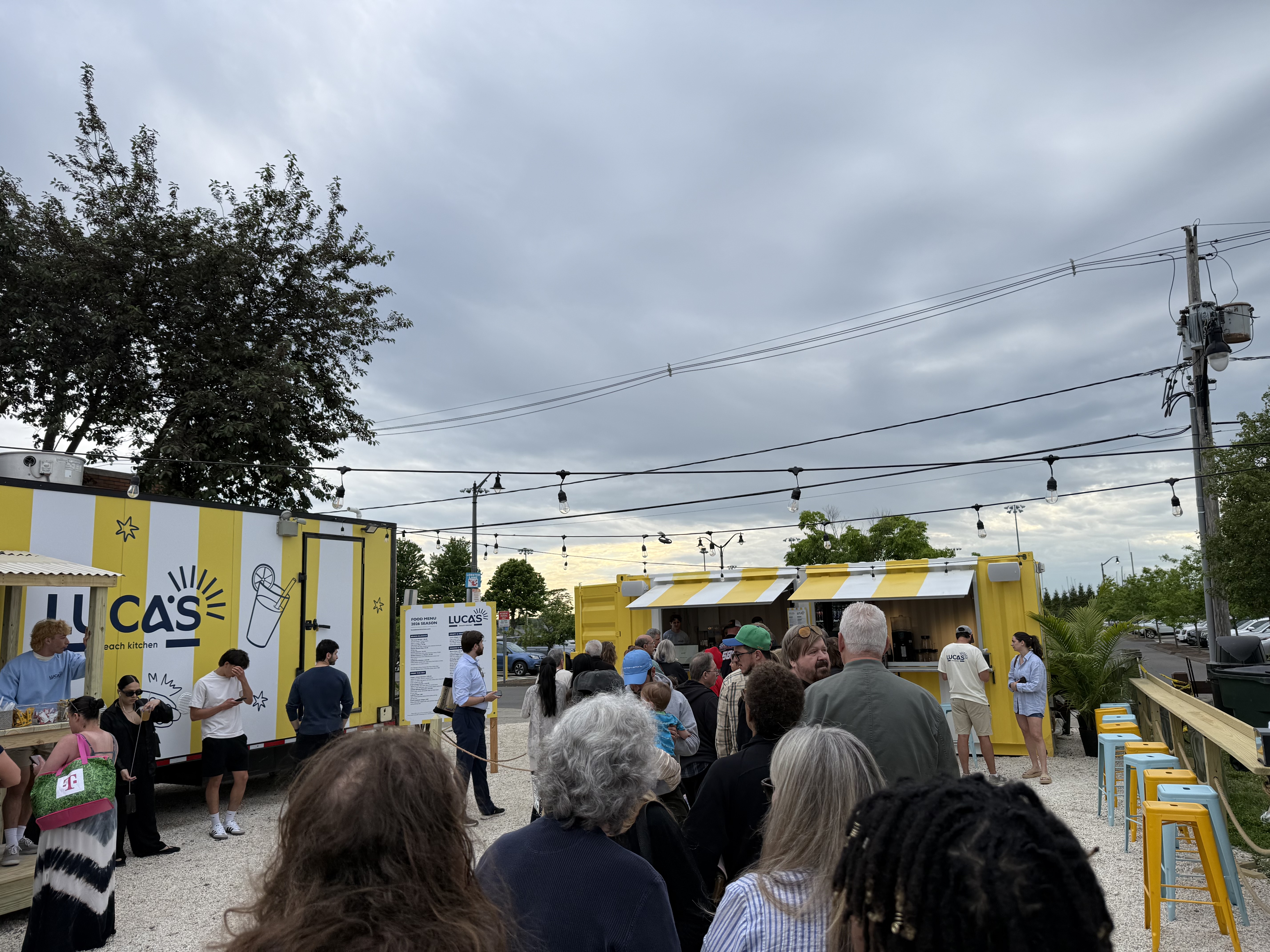 Wide view of the Luca's Beach Kitchen patio, both trailers, string lights and the opening night crowd.