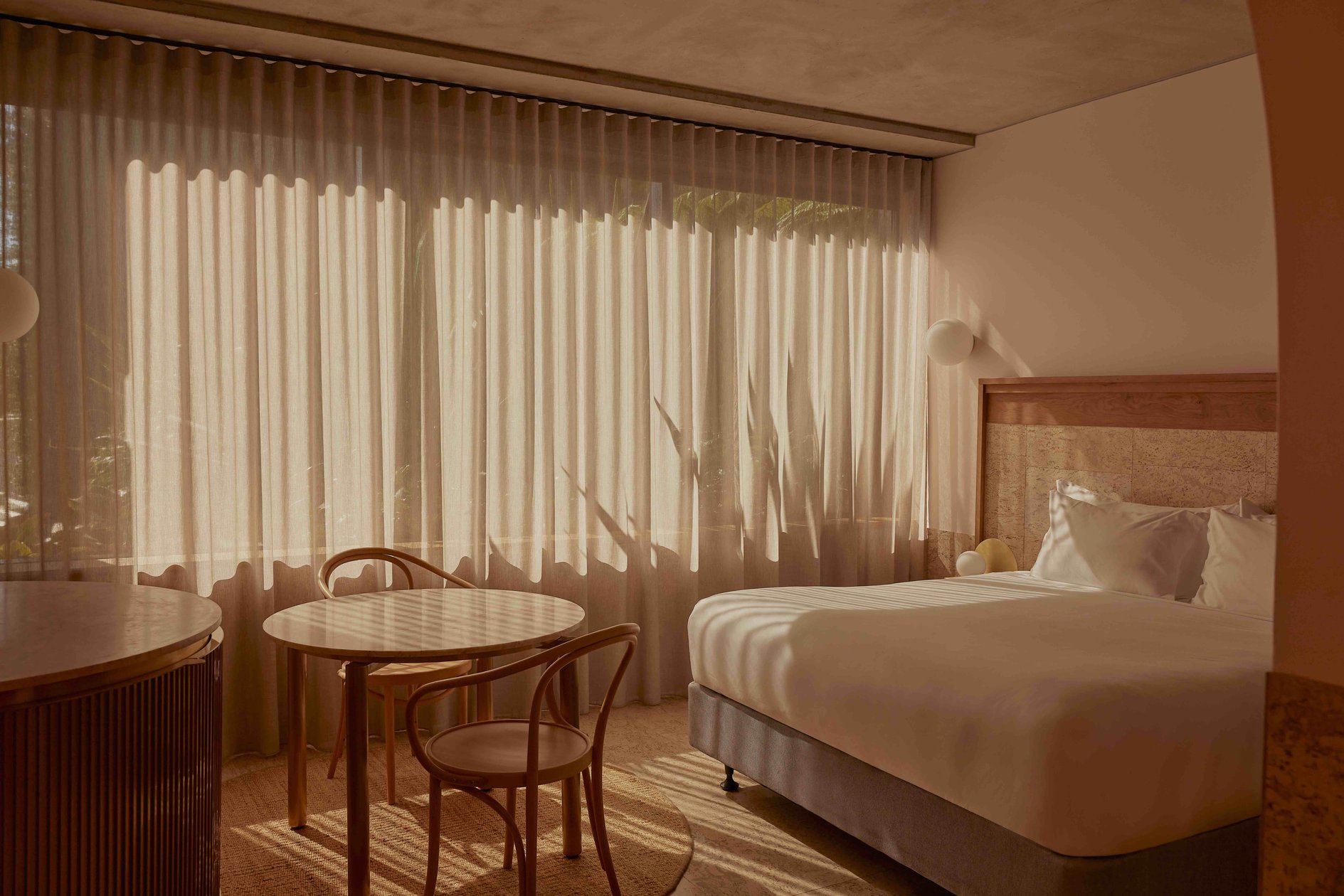 Sunlit guest room with timber furniture and soft curtains