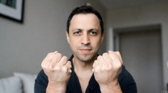 Man squeezing his hands into fists while seated