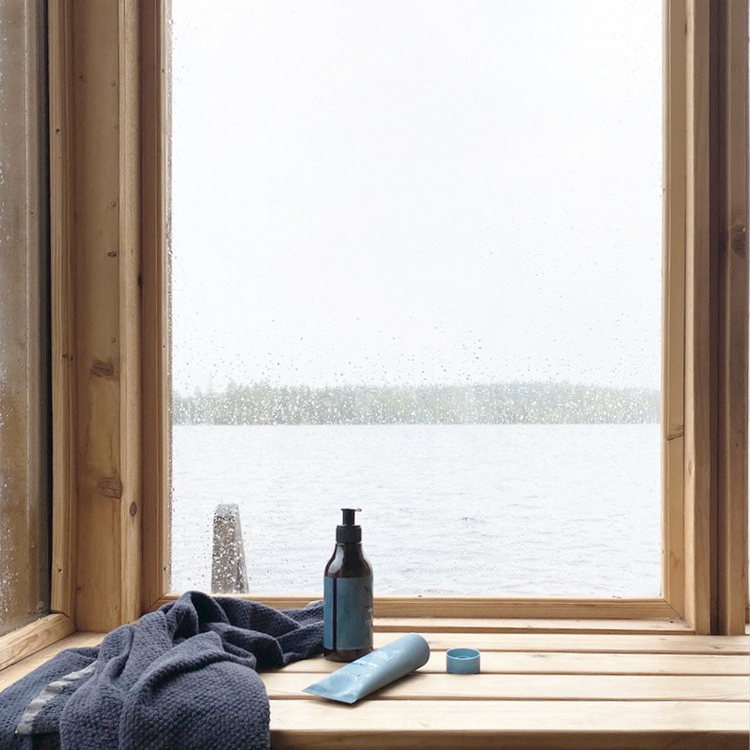 Wide hotel window with a water view, folded robe, bottle, and toiletries on the sill
