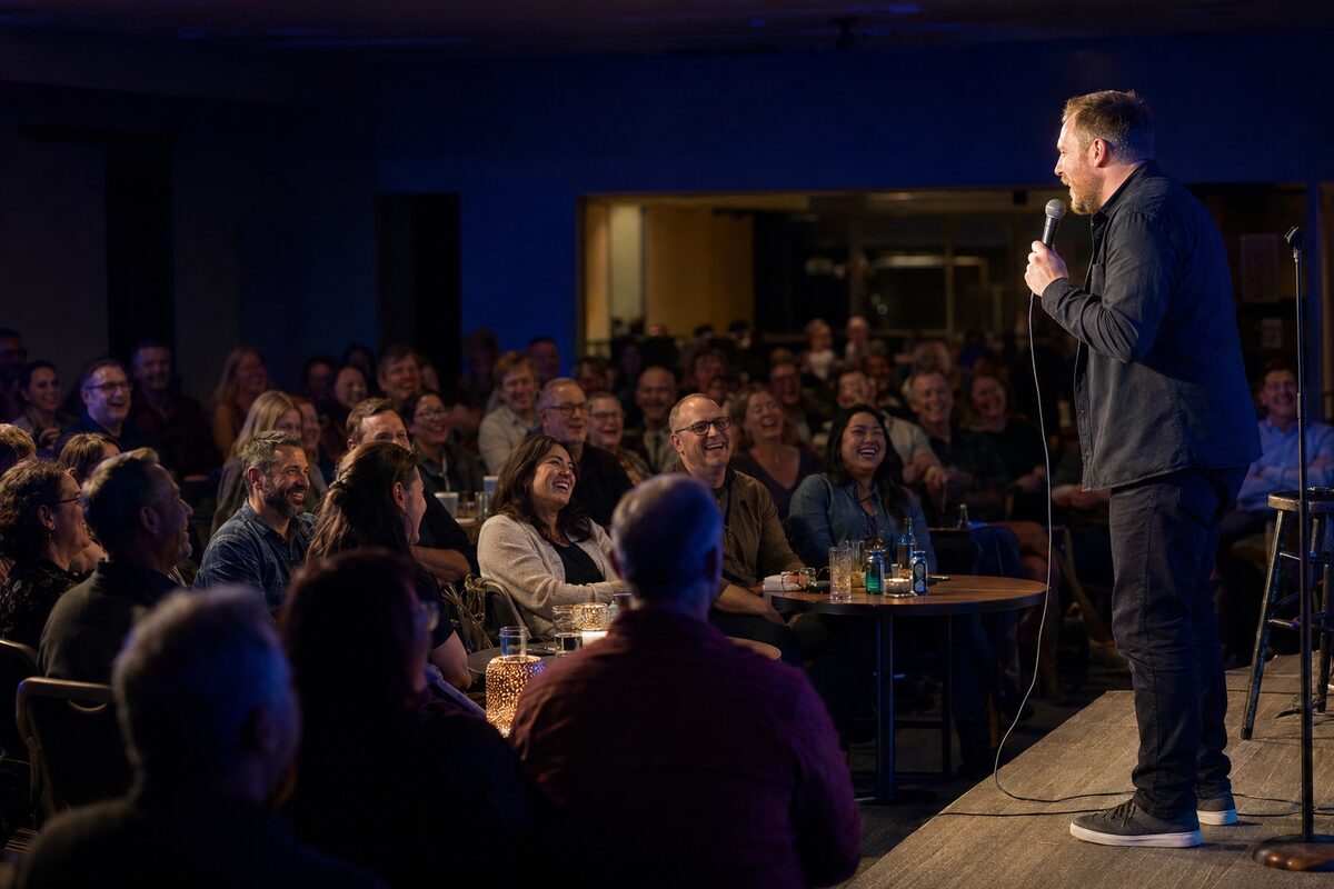 Stand-up comedian performing for a laughing audience in a community legion hall