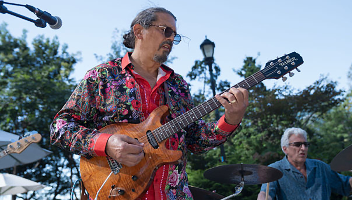Emmett Hughes playing guitar in a promotional performance photograph