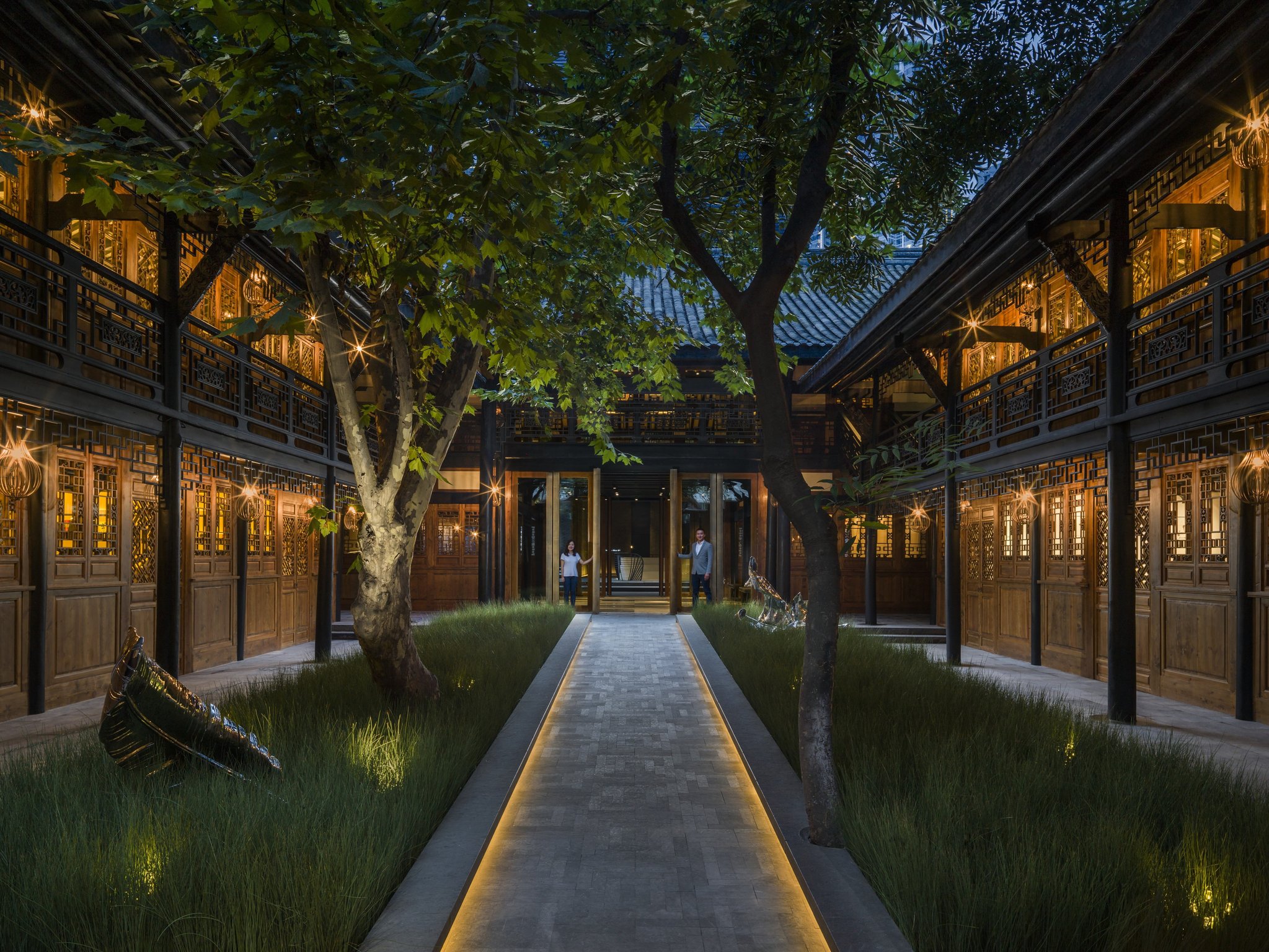 Tree-filled historic courtyard and covered walkways illuminated at night